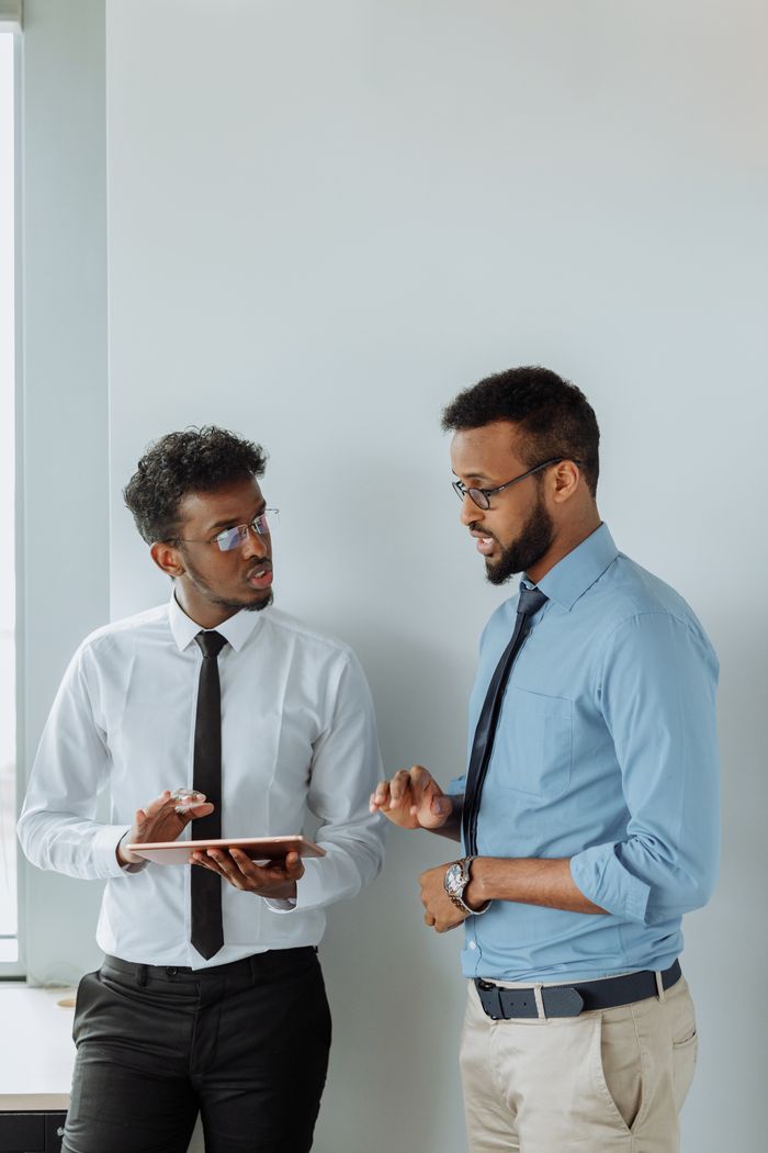 about-01 Two professionals discussing plans using a tablet in a modern office setting.